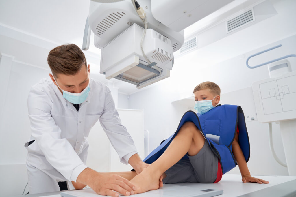 garoto na sala de exame com seu médico. Ele tem um cartão de descontos para fazer o exame de maneira mais barata
